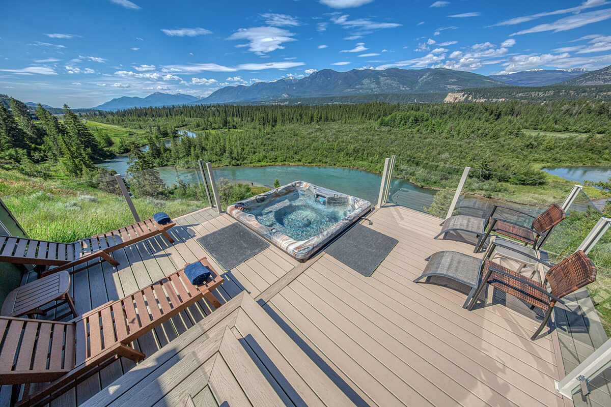 hot tub with clear water on deck with 2 sun loungers and view of river, trees and mountains