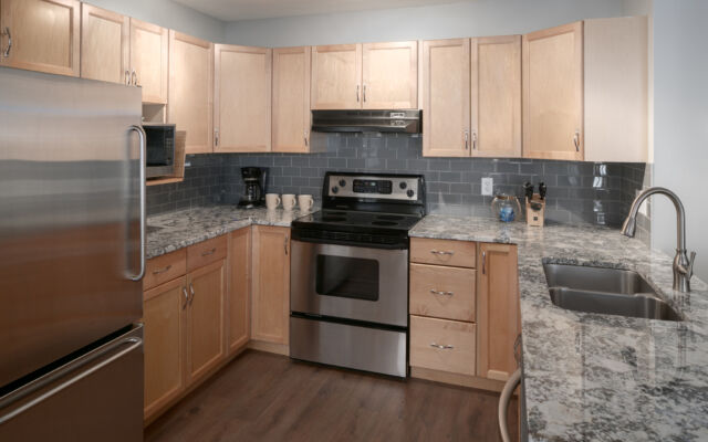 Kitchen and dining area with light wood dining table to the left, stainless steel appliances, and counterspace.