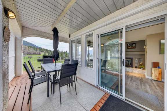 Large partially covered deck with dining table with 6 chairs, lounge seating, gas BBQ and golf course and mountain views at Tee House 3BR-13 in Mountain View Villas