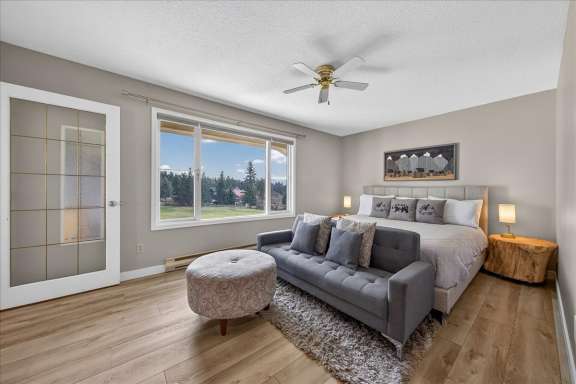 Master bedroom with king bed, seating area, Smart TV and large window with mountain and golf course views at Tee House 3BR-13 in Mountain View Villas