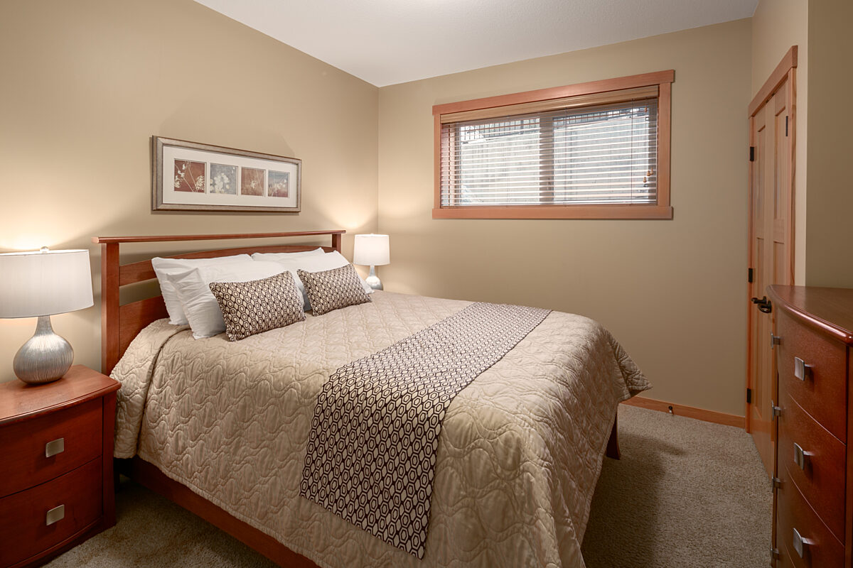 Queen bedroom with taupe bedding and window to the right.