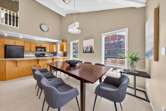 Bright dining area with a large table seating eight, adjacent to a fully equipped open-concept kitchen with a breakfast bar, vaulted ceilings and natural light in a Fairmont Creek vacation rental