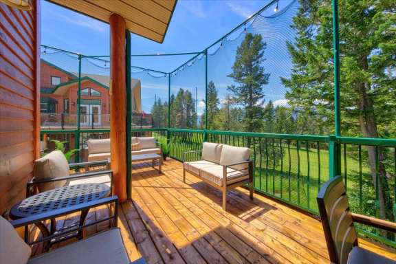 Large private deck with comfortable outdoor lounge seating, overlooking the golf course, surrounding trees and mountain views at a Fairmont Creek vacation rental