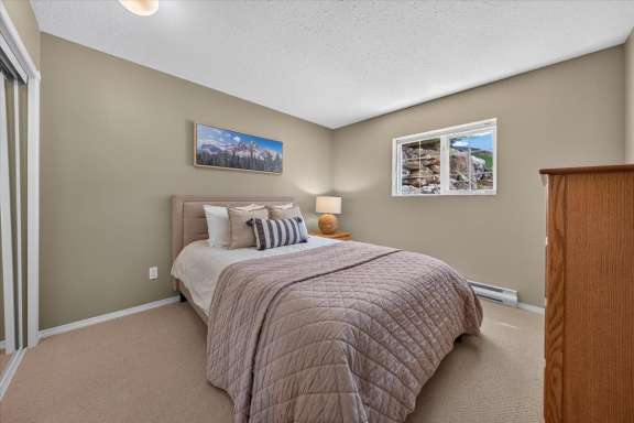 Lower-level bedroom with a queen bed, bedside table, dresser and natural light at Springs & Swings - Marble Canyon 504 - Phase 1.