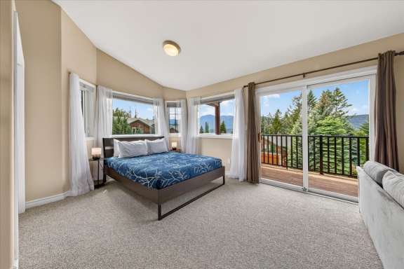 Second bedroom with queen bed, private balcony, seating area and mountain views at Marble Canyon 704 Phase 2 in Fairmont Hot Springs.