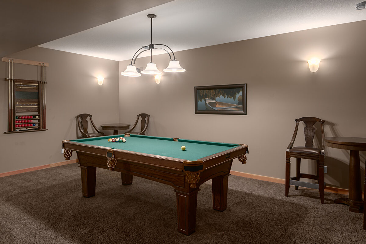 Recreation room with pool table, overhead lighting and seating areas.