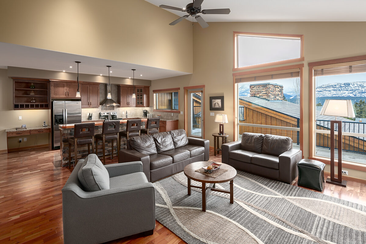 Kitchen and living space in view. Bartsools, kitchen area in background and living room furniture to the front.