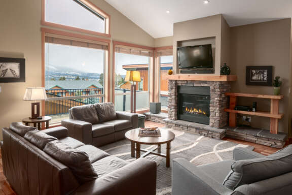 Living space with couches, television, and window to the left. Tall ceilings.