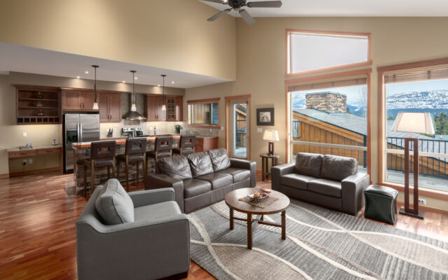 Living space with couches, television, and window to the left. Tall ceilings.