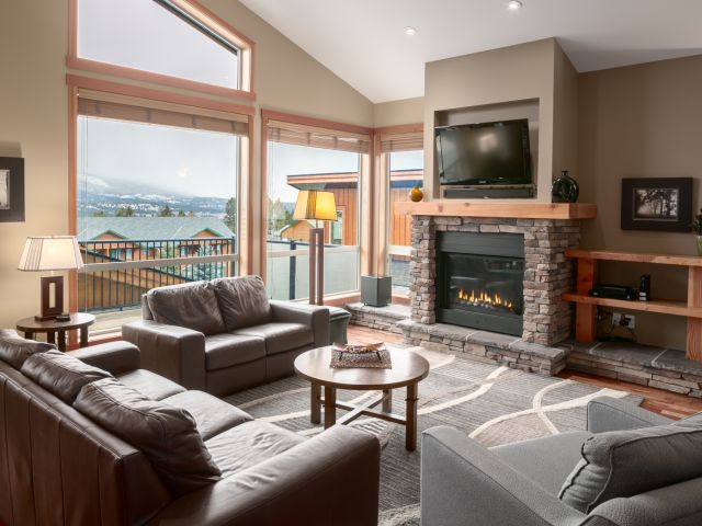 Living space with couches, television, and window to the left. Tall ceilings.