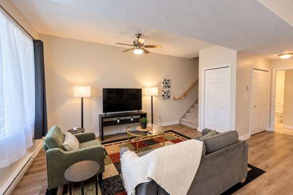 Comfortable living room at Little Falls Landing with sofa, armchair, coffee table, TV, double hide-a-bed and large windows.