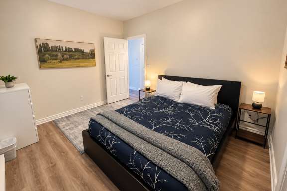 Bedroom at Little Falls Landing featuring a queen bed, bedside tables, lamps and spacious layout