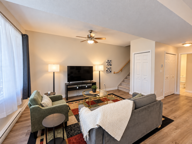 Comfortable living room at Little Falls Landing with sofa, armchair, coffee table, TV, double hide-a-bed and large windows.