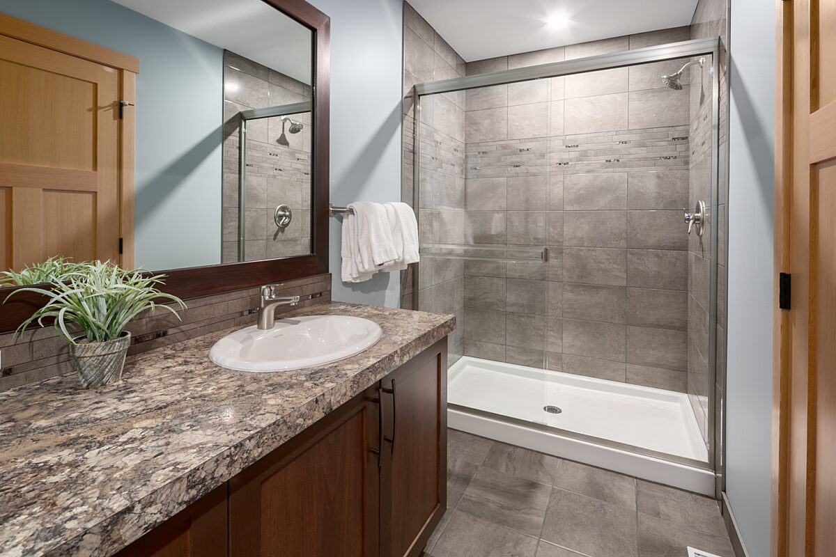 Ensuite bathroom with large shower area, sink, and mirror.
