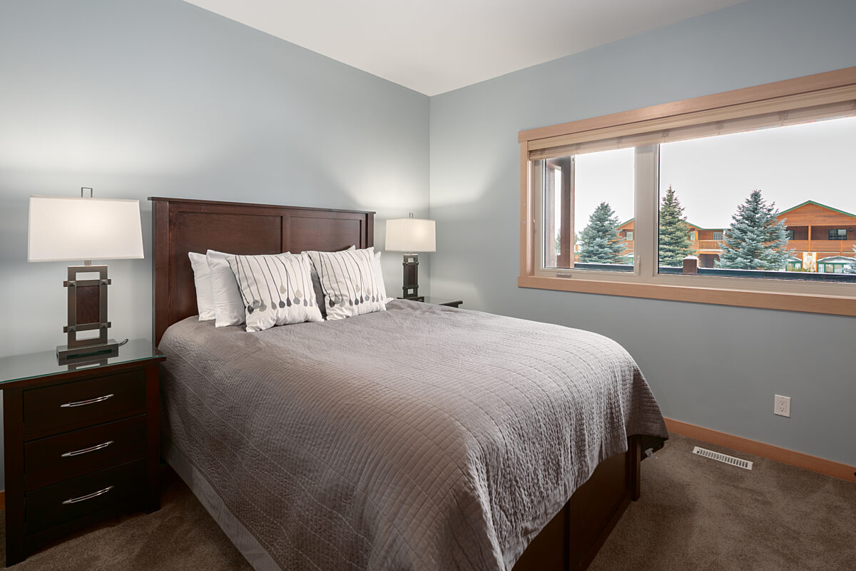 Master bedroom with king bed. Grey bedding and walls. Two bedside tables with lamps.