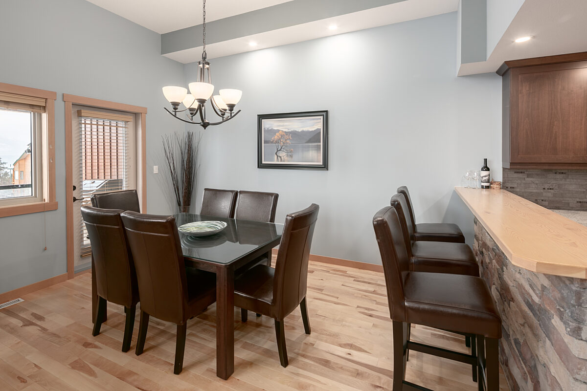 Dining room area with kitchen table and chairs. Overhead lighting above.