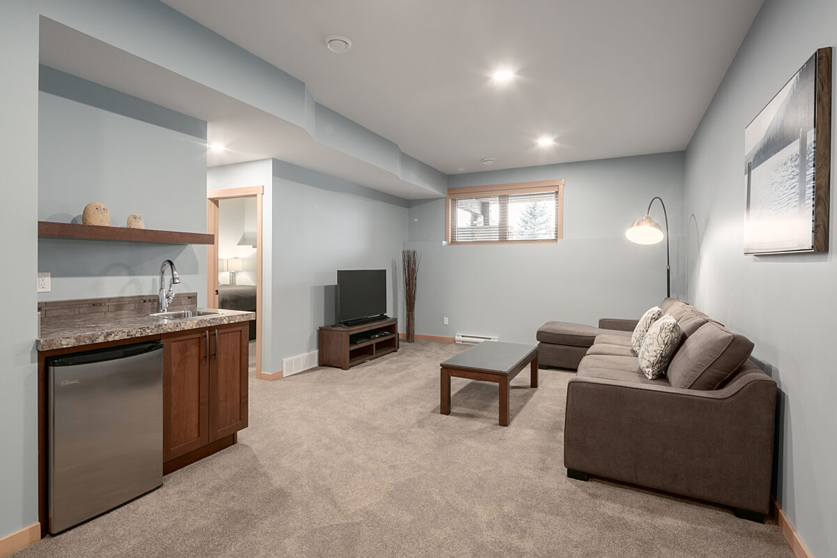 Living space in a downstairs area. Television, couch, coffee table and wet bar.