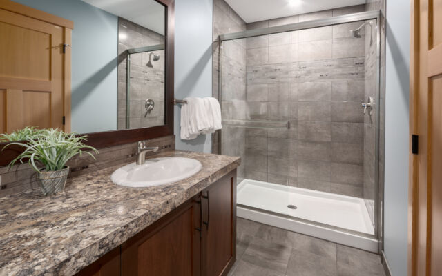 Large living room with windows to the right. Television above, two couches, one chair and coffee table.
