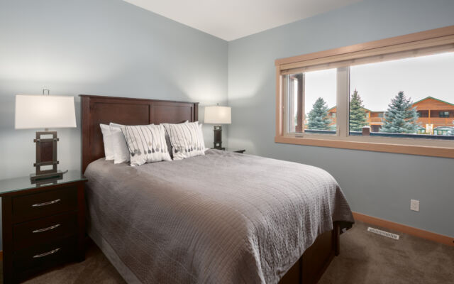 Large living room with windows to the right. Television above, two couches, one chair and coffee table.