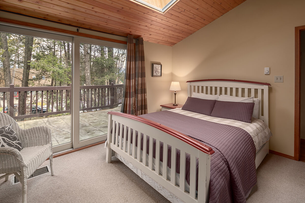 Master bedroom with queen bed. Large window to the left.