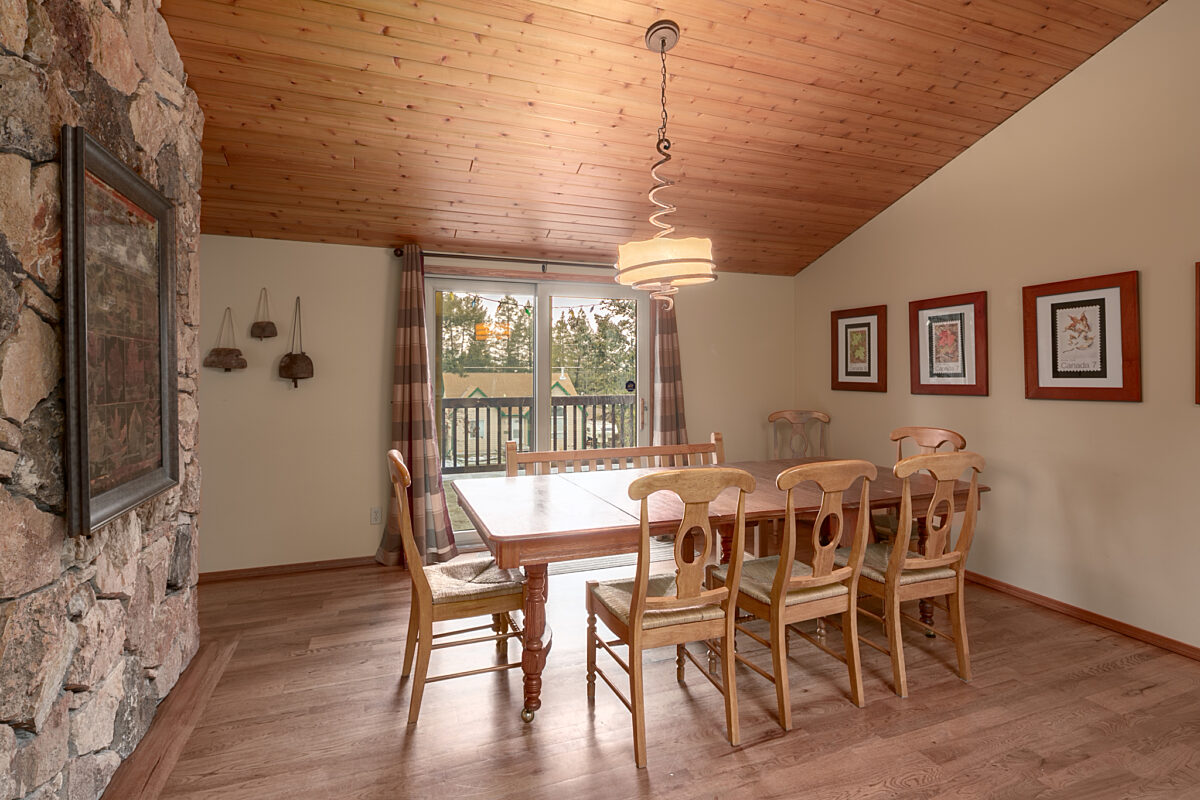 Dining area with eight chairs around the table. Large window behind the table and paintings to the right.