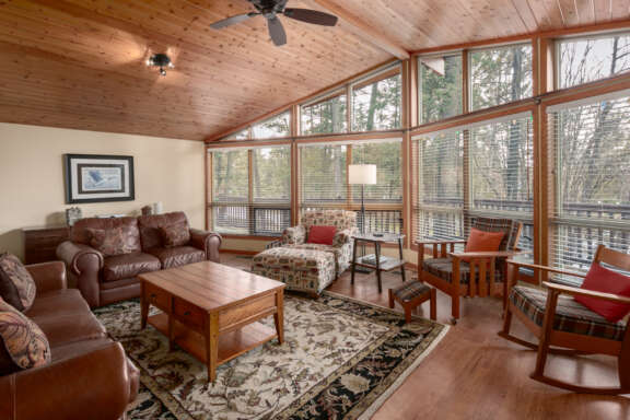 Large living room with wall of windows to the right. Ample seating area, coffee table, and rug.