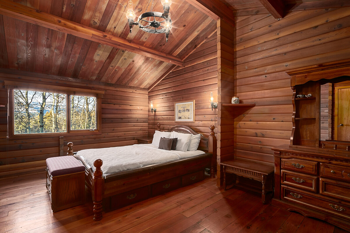 Master bedroom with king bed. Rustic interior with wood panelling.