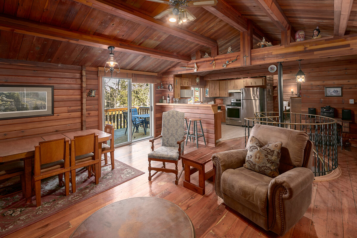 Living space with chairs, dining area. Patio doors to the left, kitchen to the distance on the right.