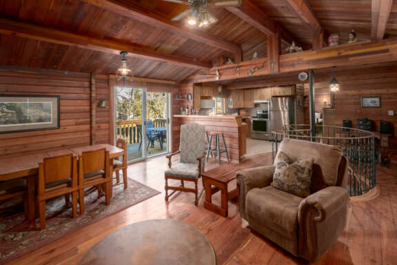 Living space with chairs, dining area. Patio doors to the left, kitchen to the distance on the right.