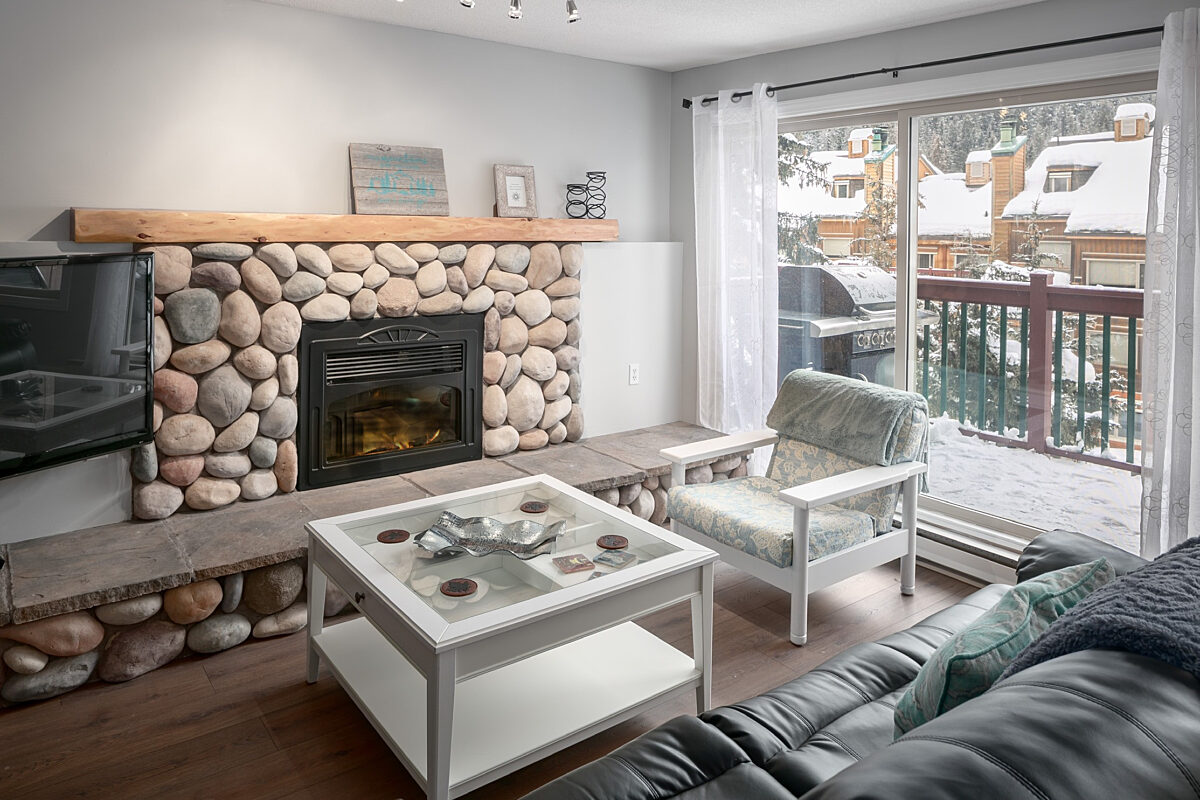 Rock fireplace with seating area, chairs, and couches. Glass doors to the right leading to patio.