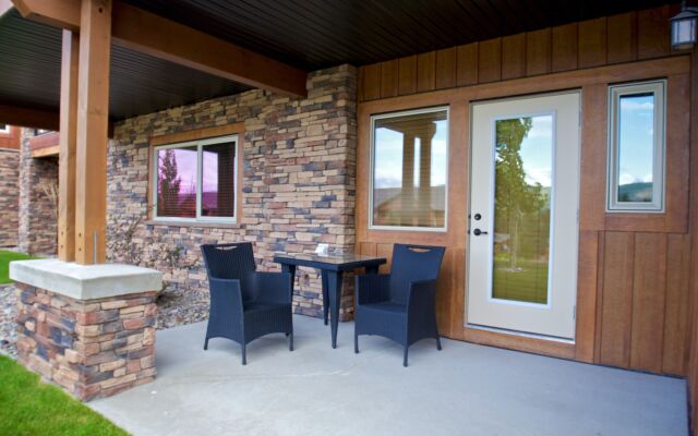 Living room area with couches, windows to the left, stone fireplace and television.