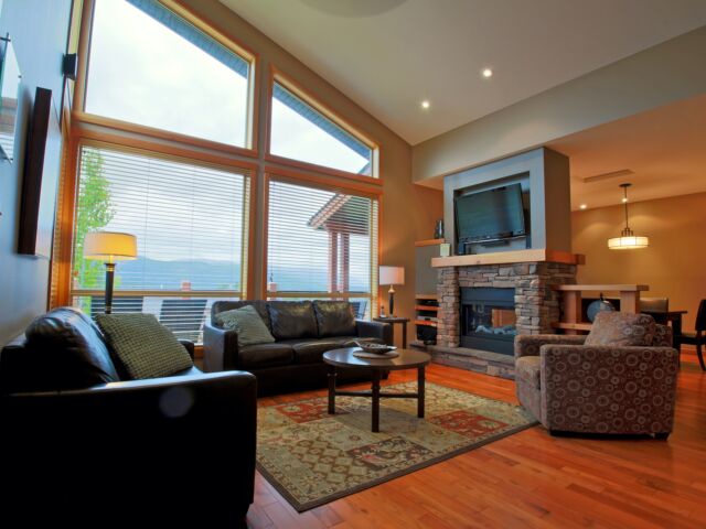 Living room area with couches, windows to the left, stone fireplace and television.