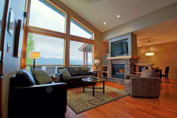 Living room area with couches, windows to the left, stone fireplace and television.