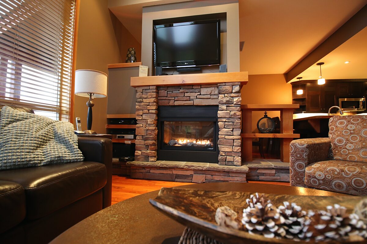 Stone fireplace with television mounted on top. Seating area and couches nearby.