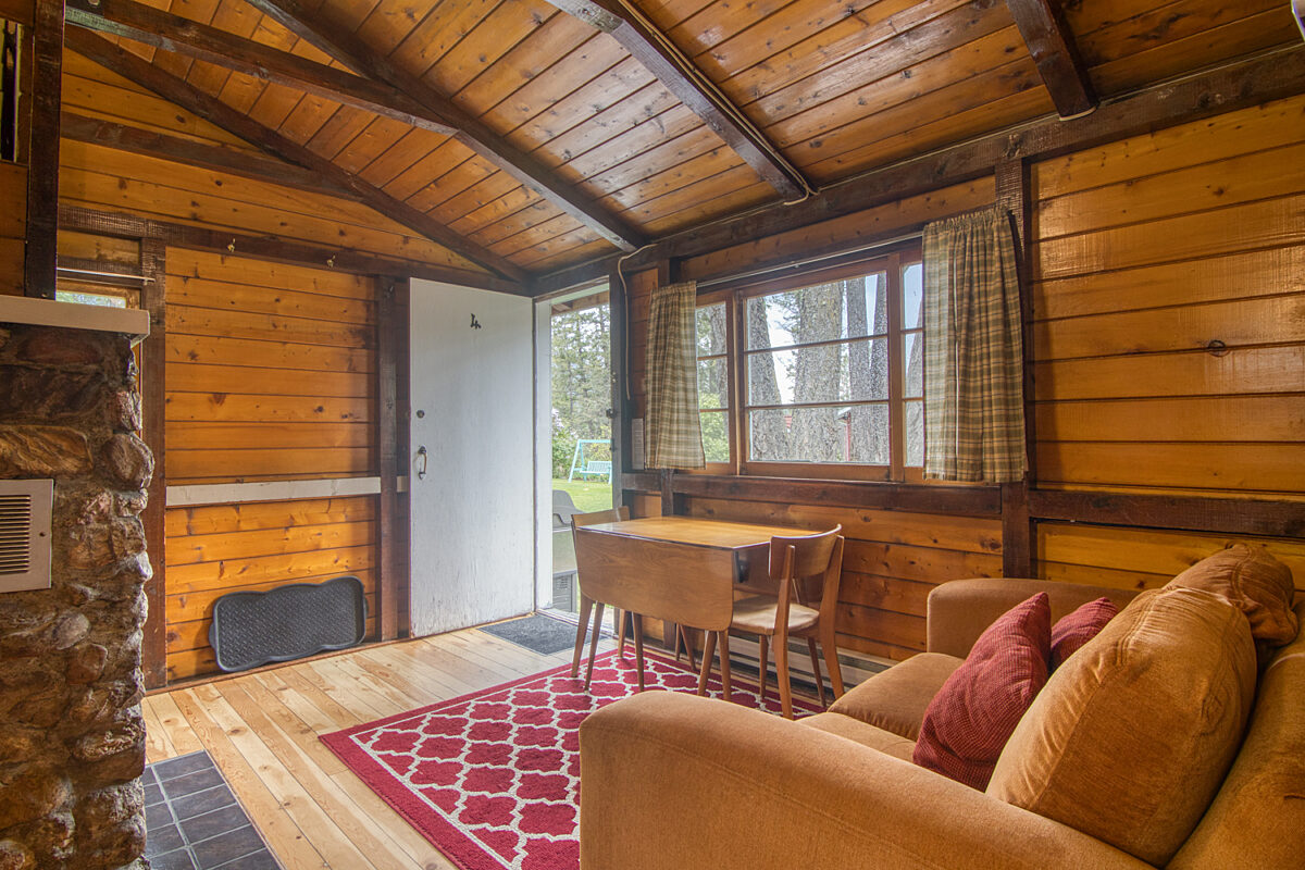 Living and dining area in wood panelled cabin.