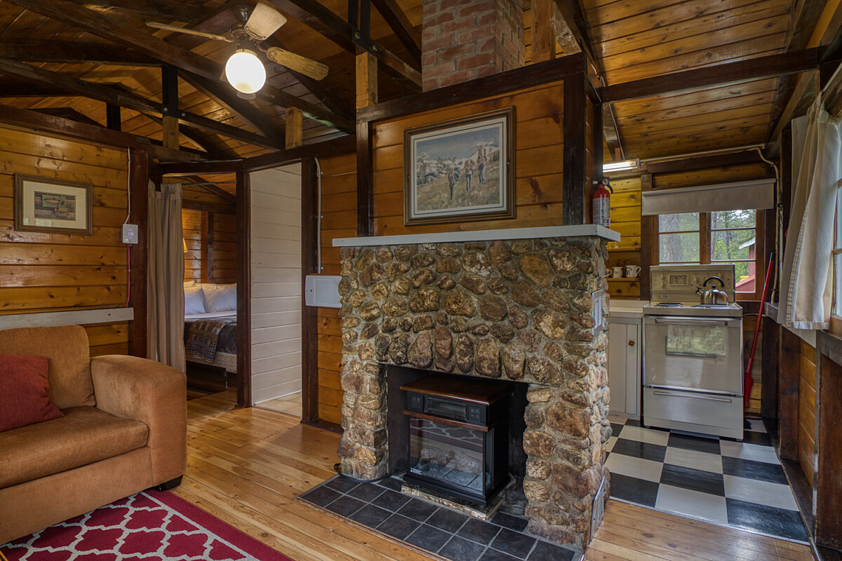 Stone fireplace in wood panelled cabin living room.