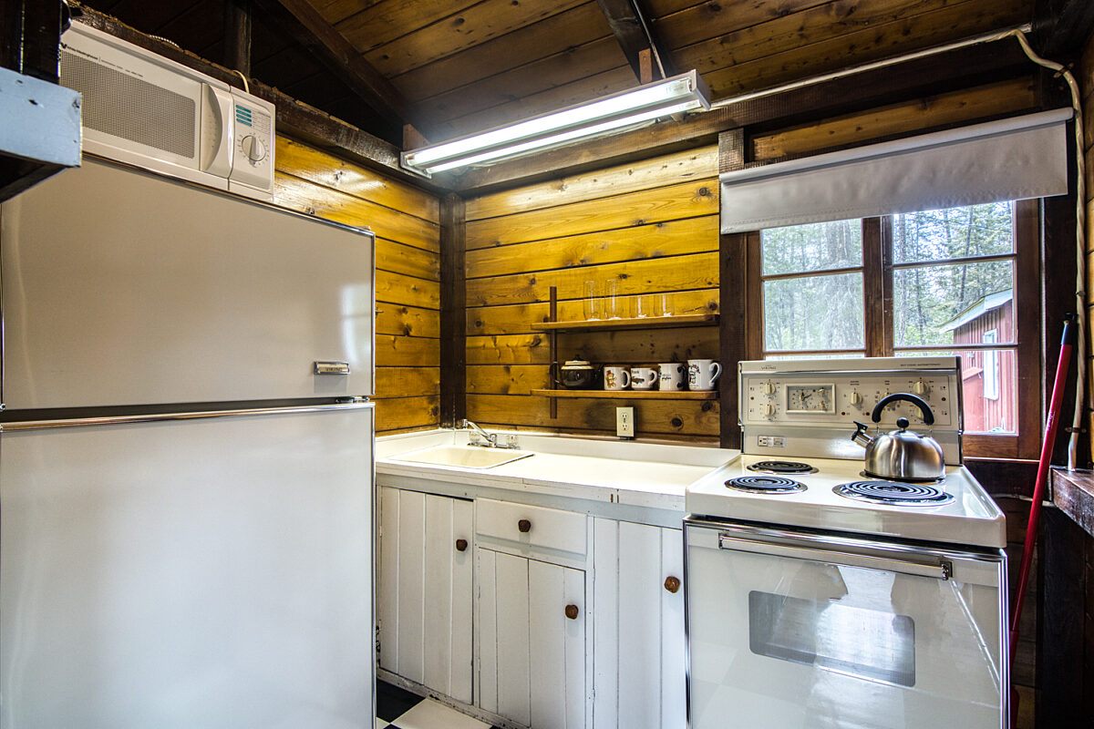 Wood panelled cabin kitchen with white appliances.