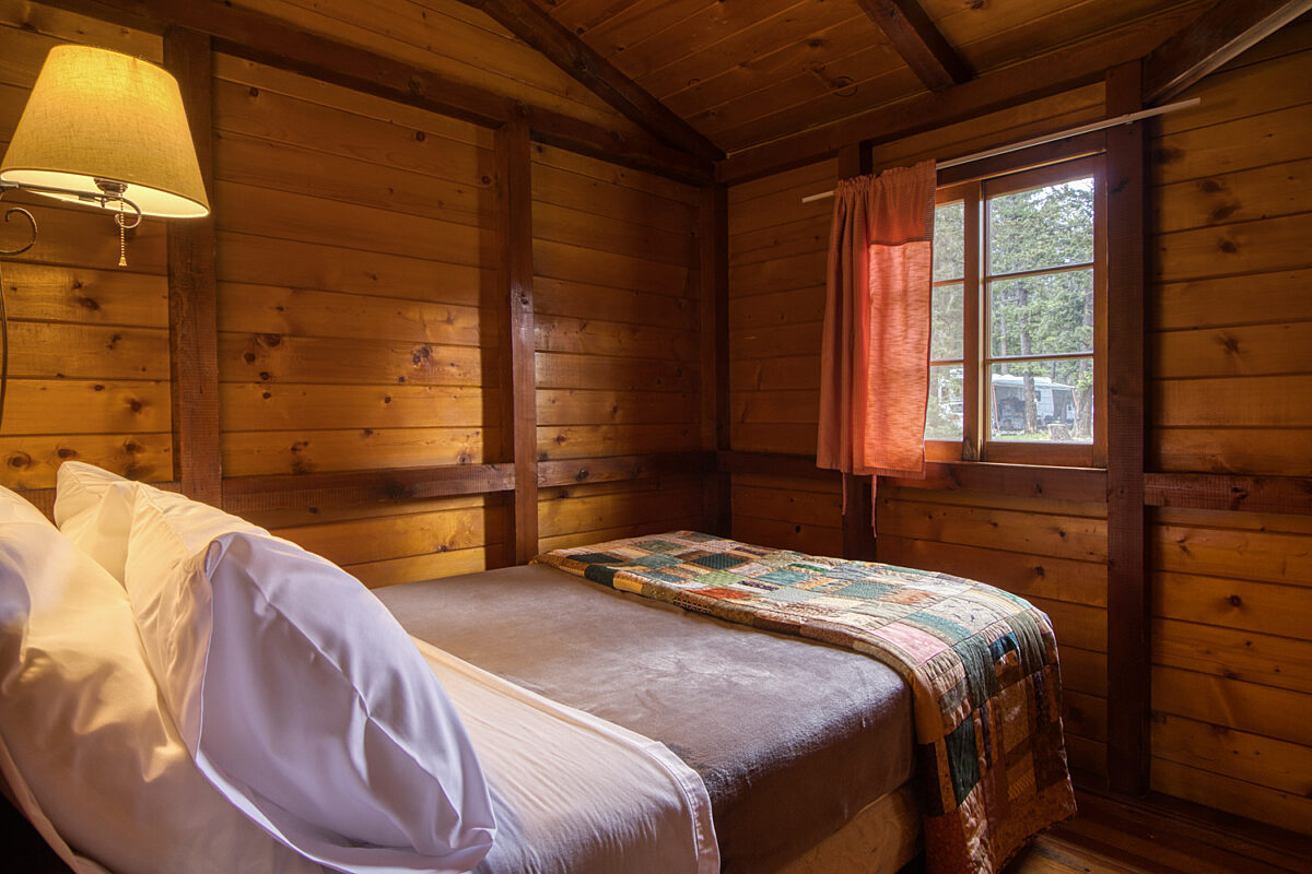 Double bed in wood panelled cabin bedroom.