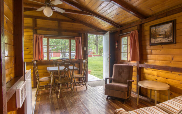 Outdoor living space with two red chairs, lilac bushes, and greenery.