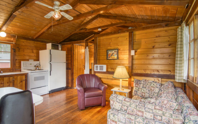 Outdoor living space with two red chairs and teal swing.