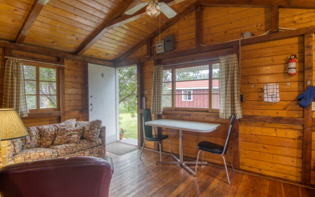 Outdoor living space with two red chairs and teal swing.