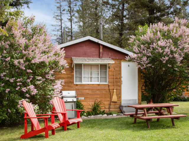 Outdoor living space with two red chairs and teal swing.
