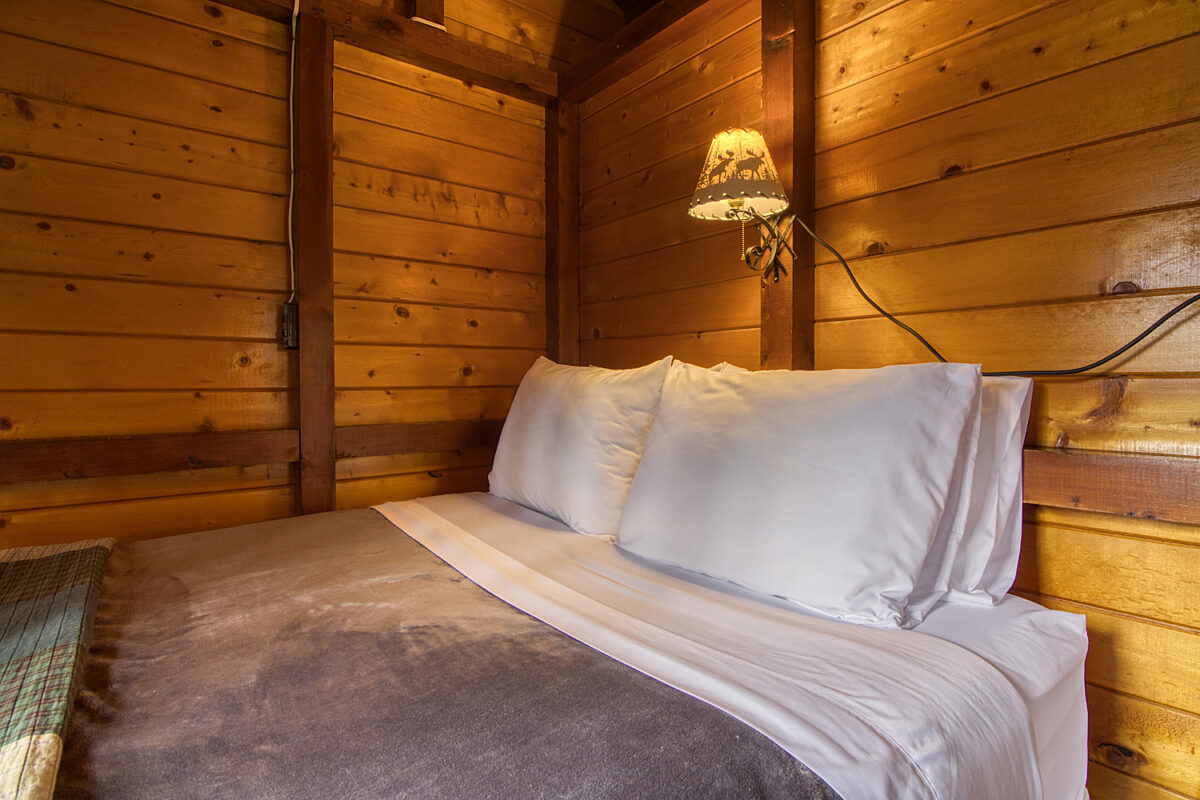 Double bed in wood panelled cabin bedroom.