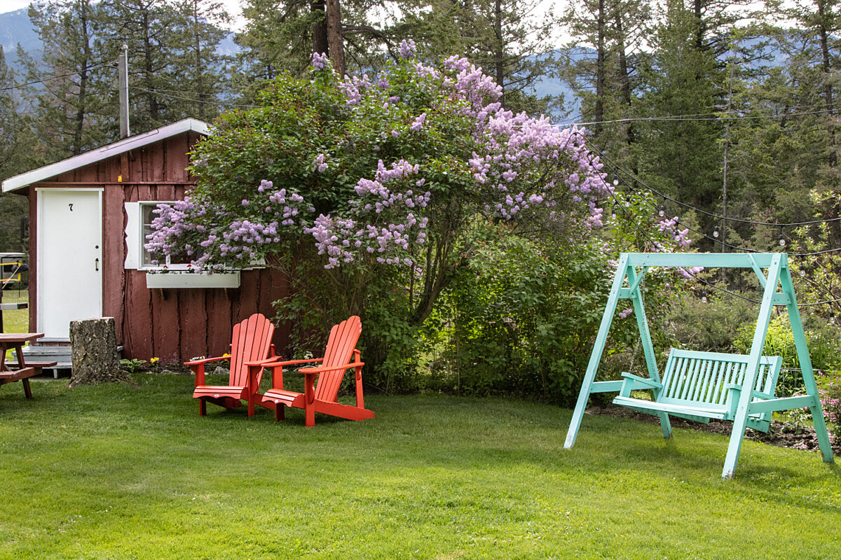 Outdoor living space with two red chairs and teal swing.
