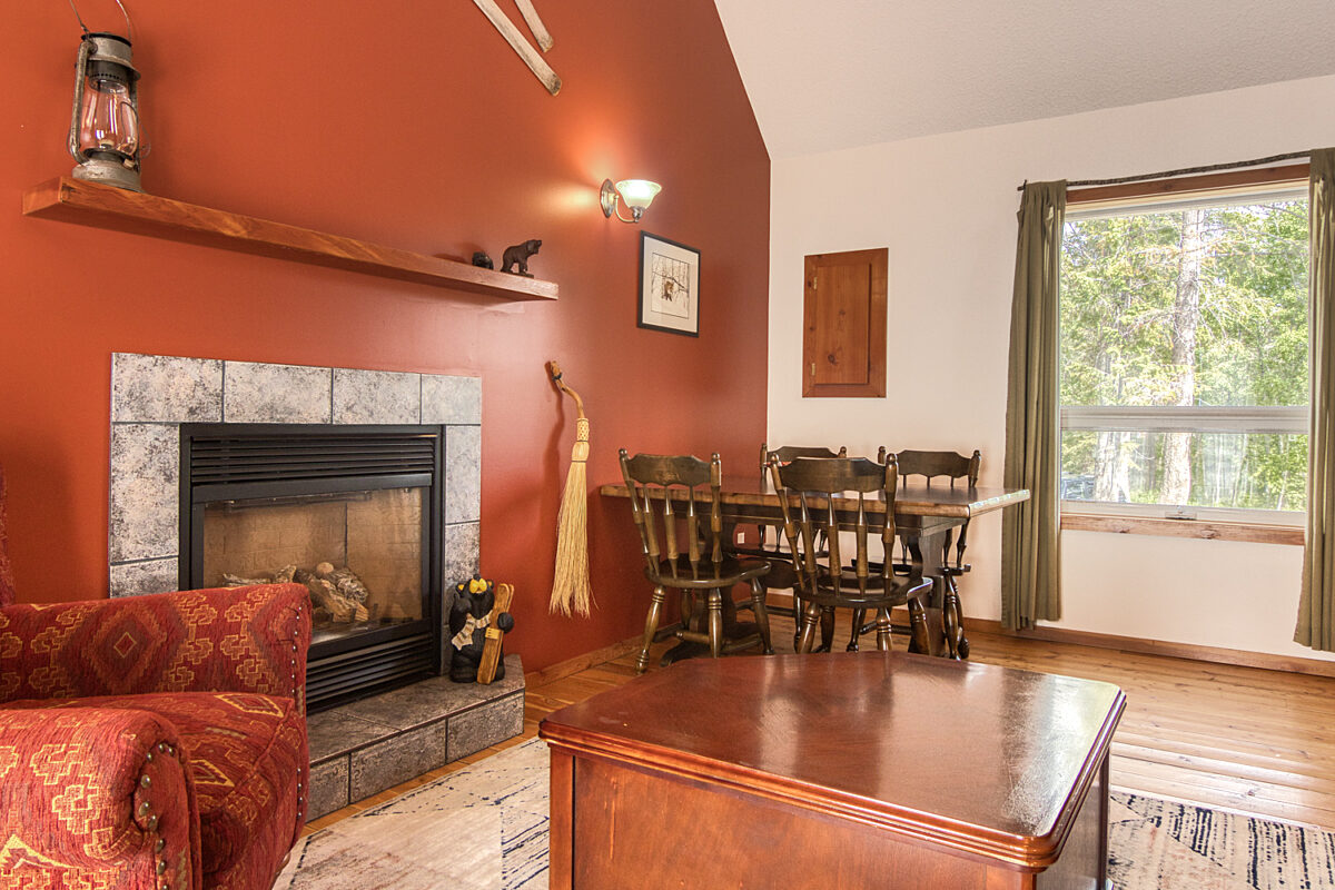 Fireplace to the left of the frame with red walls, red couch, and dining table and chairs to the right.