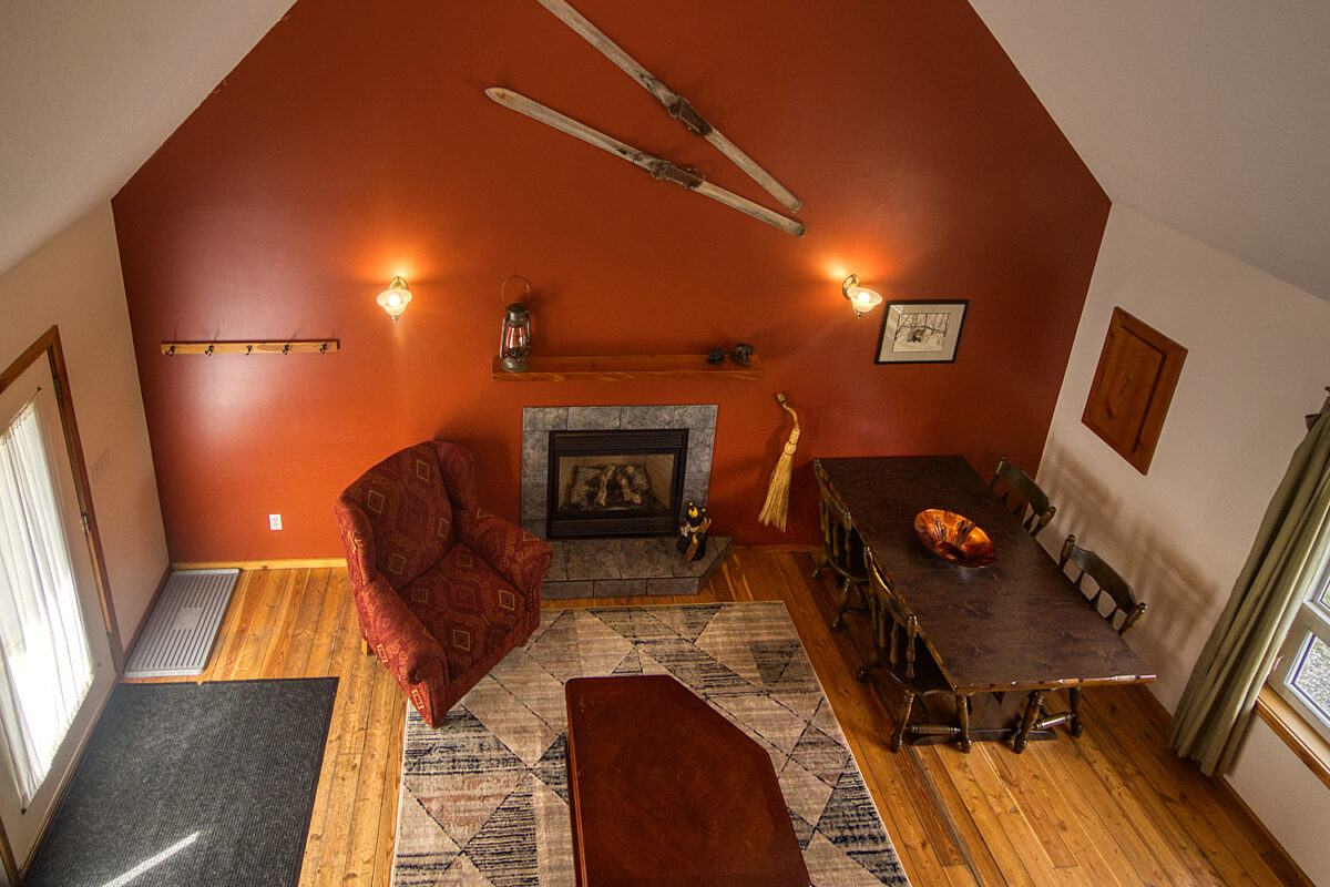 View of living and dining room with red walls, red chairs, and brown dining room table from loft.