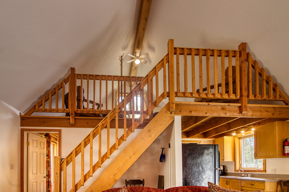 Loft with wooden stairs and wooden railings.