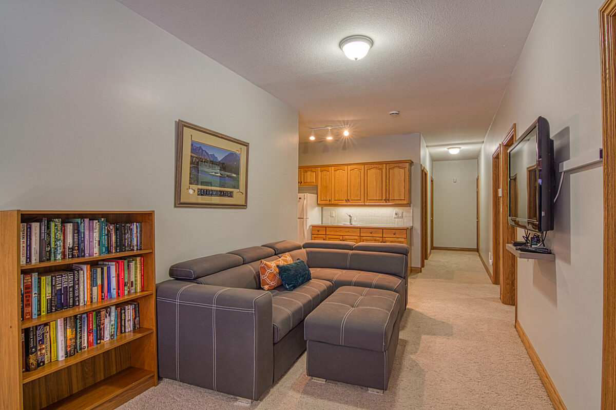 Living space with couch, bookshelf filled with books, and wet bar