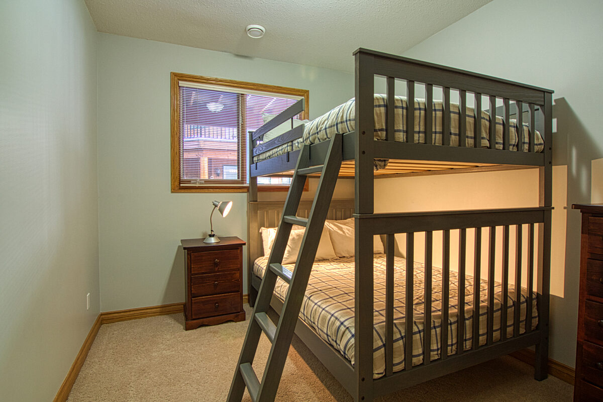 Queen bunk bed in a white room with a window.