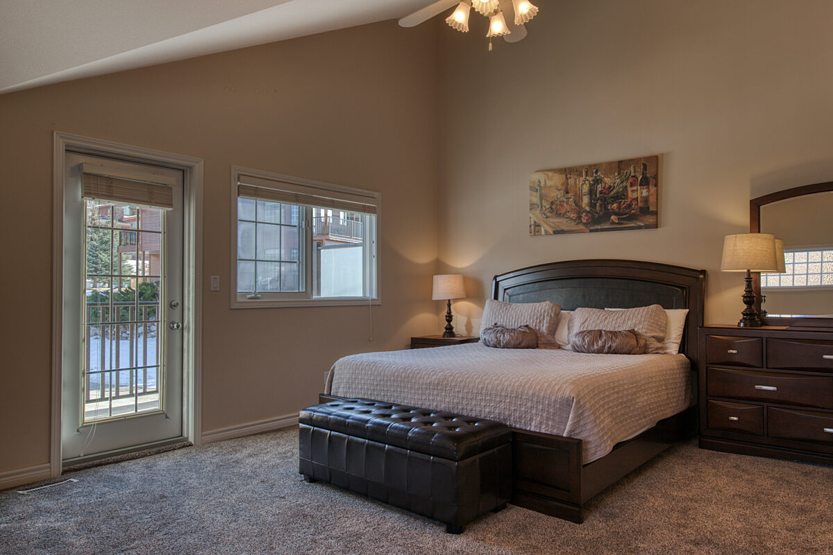 Master bedroom with walk out deck, two bedside tables with lamps.